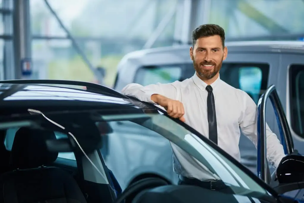 handsome man posing near luxury car showroom